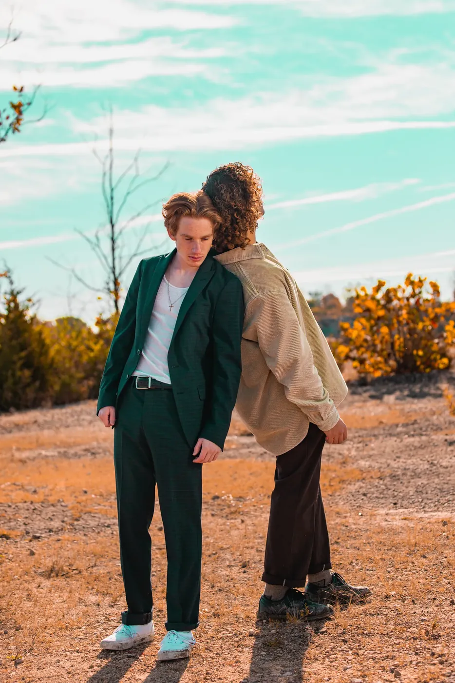 Two people in tailored clothing photographed in open desert scrub.