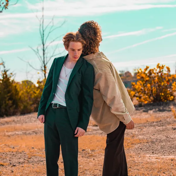 Two people in tailored clothing photographed in open desert scrub.