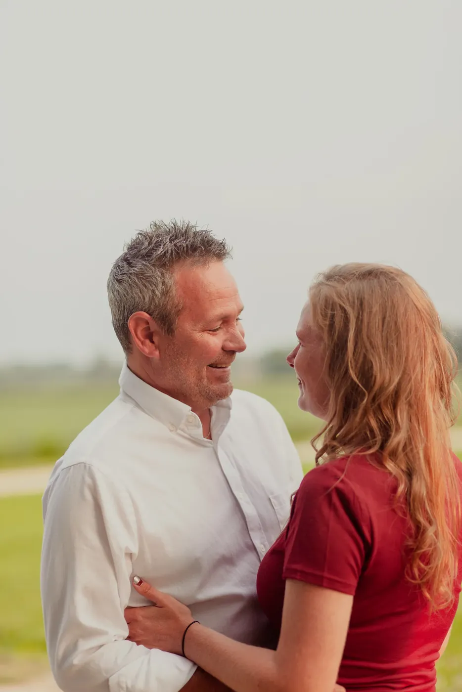 A couple photographed close together against a pale background.