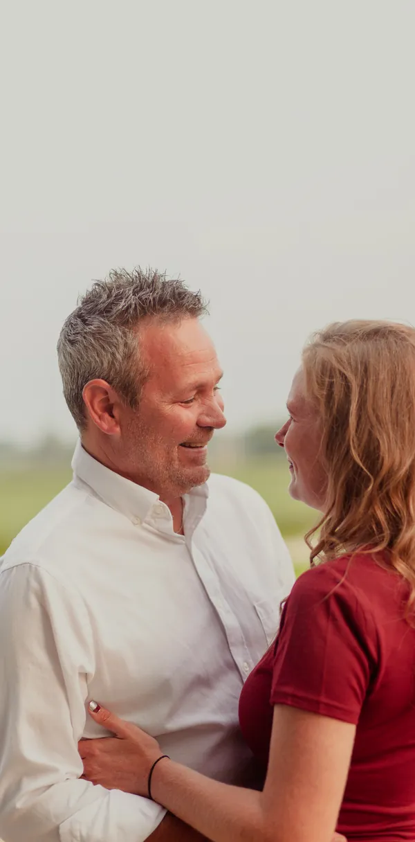 A couple photographed close together against a pale background.