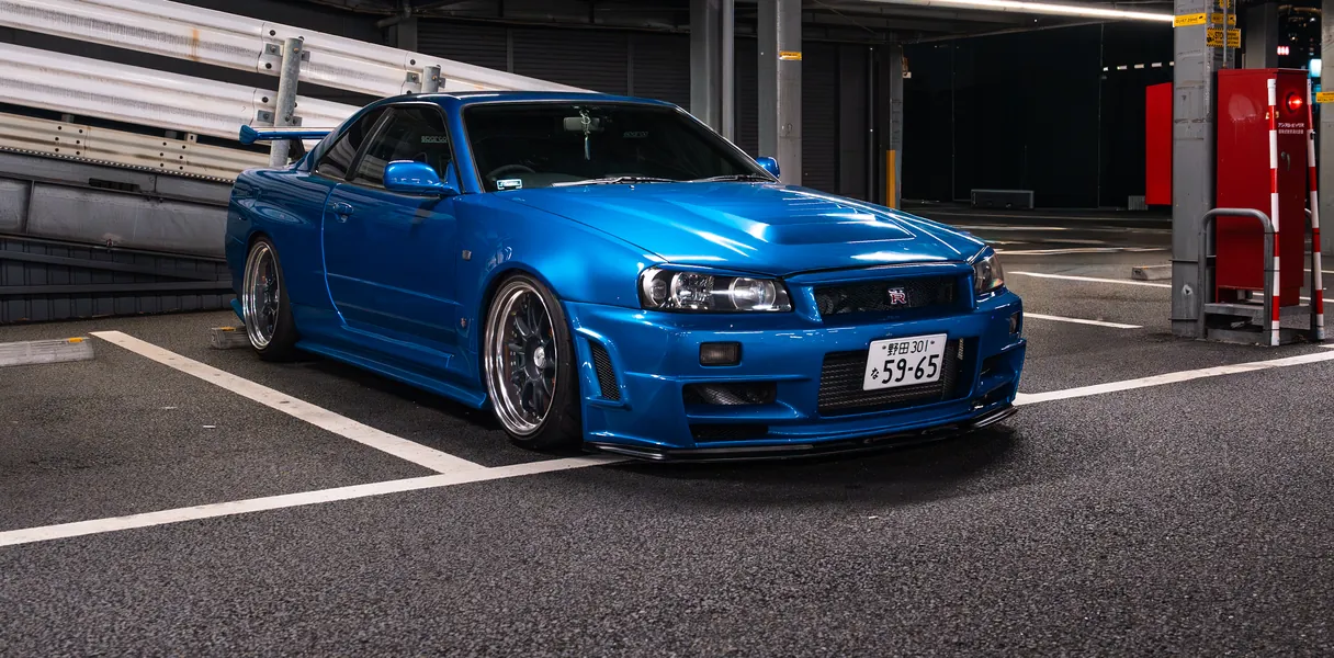 A blue Nissan Skyline GT-R in a covered parking structure.