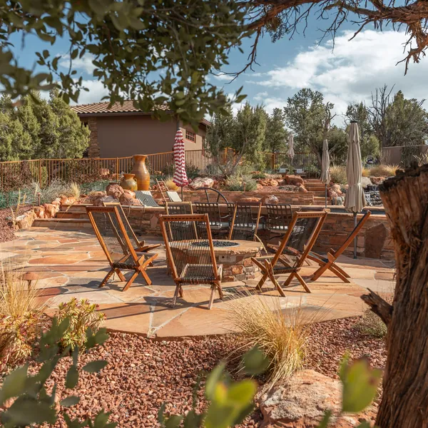 An outdoor dining terrace with a fire pit and desert planting.