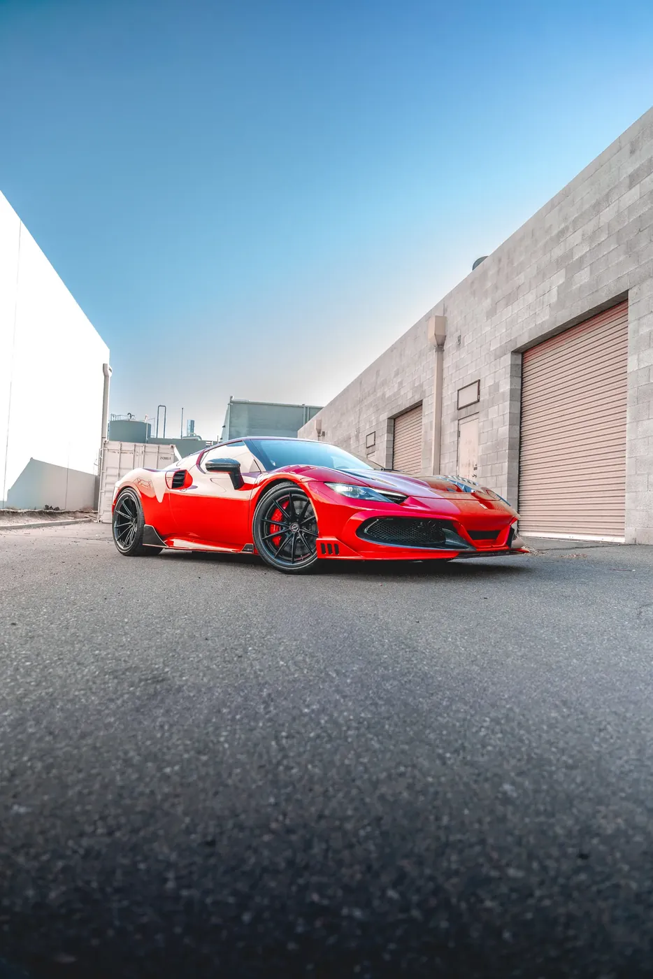 A red mid-engined sports car outside an industrial unit.