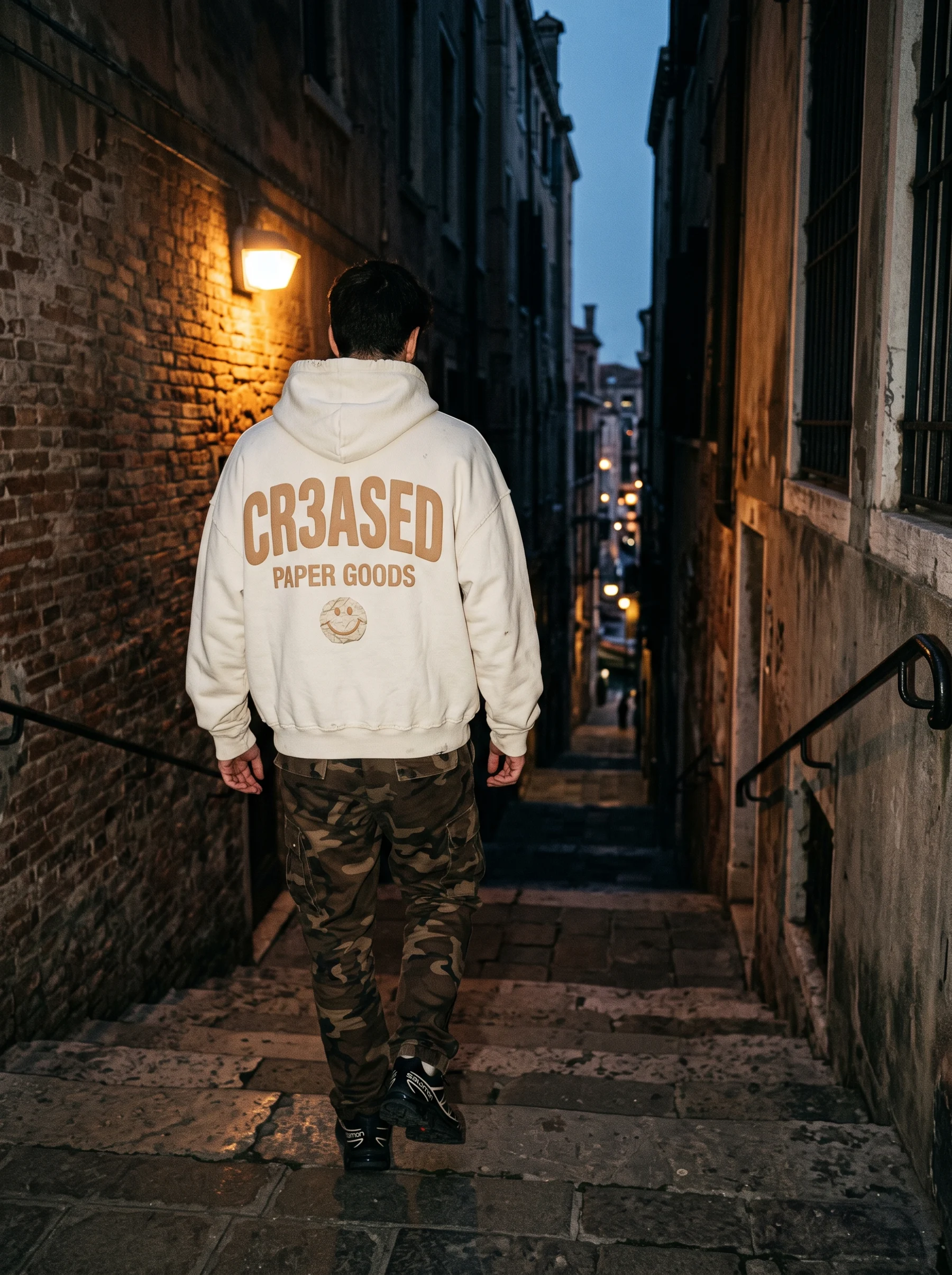 Model walking down brick stairs at blue hour in the Bone hoodie, back graphic visible